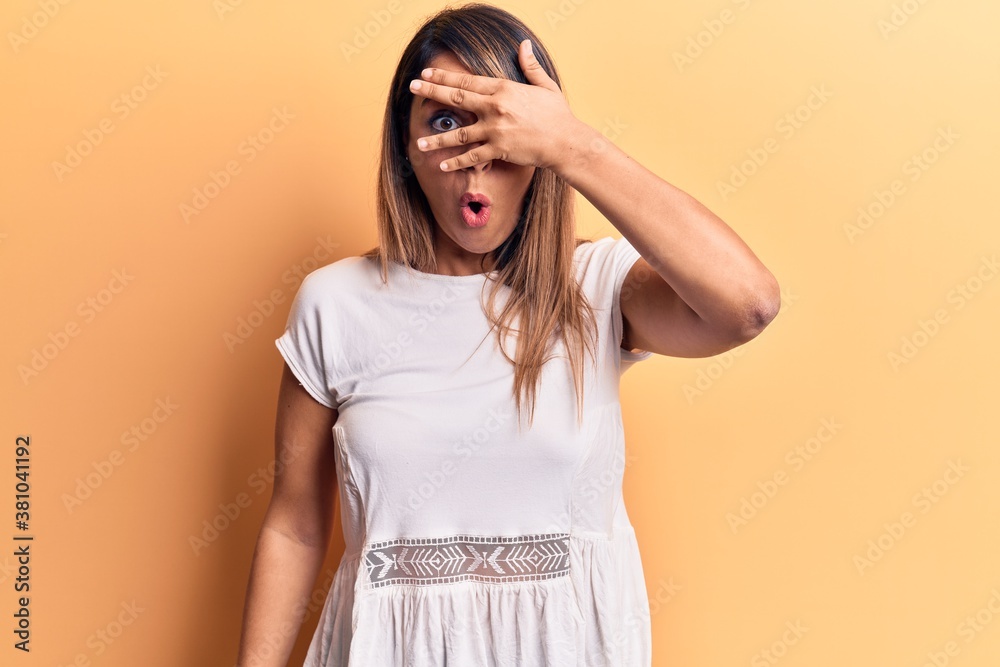 Young beautiful woman wearing casual t shirt peeking in shock covering face and eyes with hand, looking through fingers afraid Young beautiful woman wearing casual t shirt peeking in shock covering face and eyes with hand, looking through fingers afraid