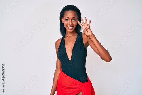 Young african american woman wearing swimsuit showing and pointing up with fingers number four while smiling confident and happy. photo