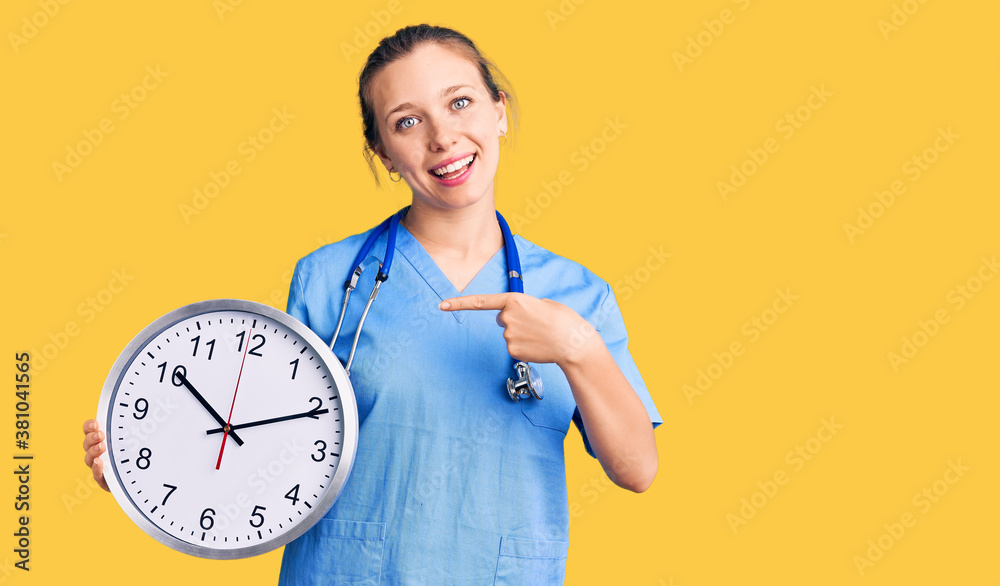 Young beautiful blonde woman wearing doctor uniform and stethoscope smiling happy pointing with hand and finger Young beautiful blonde woman wearing doctor uniform and stethoscope smiling happy pointing with hand and finger