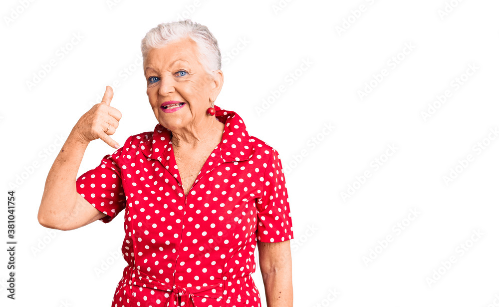 Senior beautiful woman with blue eyes and grey hair wearing a red summer dress smiling doing phone gesture with hand and fingers like talking on the telephone. communicating concepts. Senior beautiful woman with blue eyes and grey hair wearing a red summer dress smiling doing phone gesture with hand and fingers like talking on the telephone. communicating concepts.