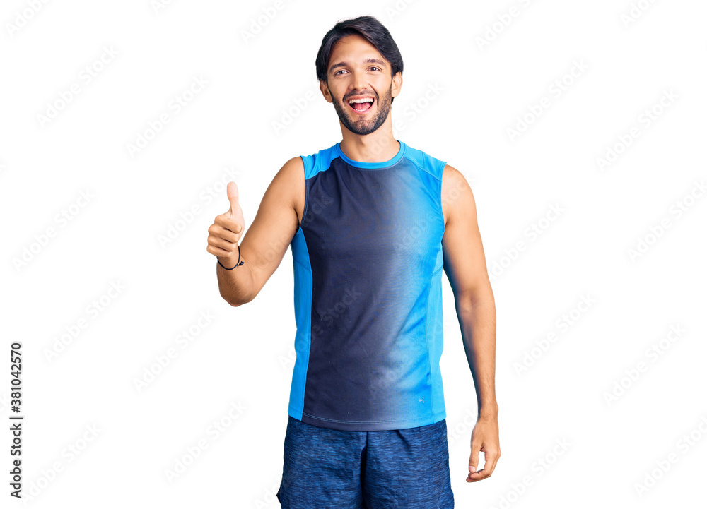 Fototapeta premium Handsome hispanic man wearing sportswear doing happy thumbs up gesture with hand. approving expression looking at the camera showing success.