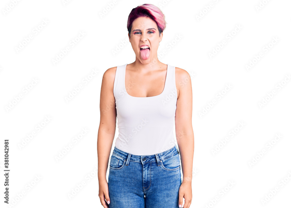 Young beautiful woman with pink hair wearing casual clothes sticking tongue out happy with funny expression. emotion concept. Young beautiful woman with pink hair wearing casual clothes sticking tongue out happy with funny expression. emotion concept.