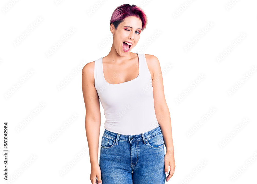 Young beautiful woman with pink hair wearing casual clothes winking looking at the camera with sexy expression, cheerful and happy face. Young beautiful woman with pink hair wearing casual clothes winking looking at the camera with sexy expression, cheerful and happy face.