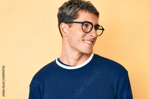 Young handsome man wearing casual clothes and glasses looking to side, relax profile pose with natural face and confident smile. © Krakenimages.com