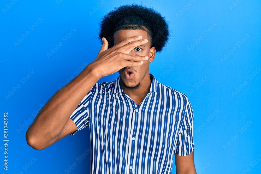 African american man with afro hair wearing casual clothes peeking in shock covering face and eyes with hand, looking through fingers afraid African american man with afro hair wearing casual clothes peeking in shock covering face and eyes with hand, looking through fingers afraid