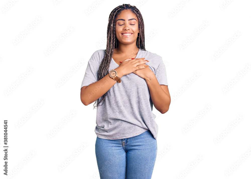 Young african american woman with braids wearing casual clothes smiling with hands on chest with closed eyes and grateful gesture on face. health concept. Young african american woman with braids wearing casual clothes smiling with hands on chest with closed eyes and grateful gesture on face. health concept.