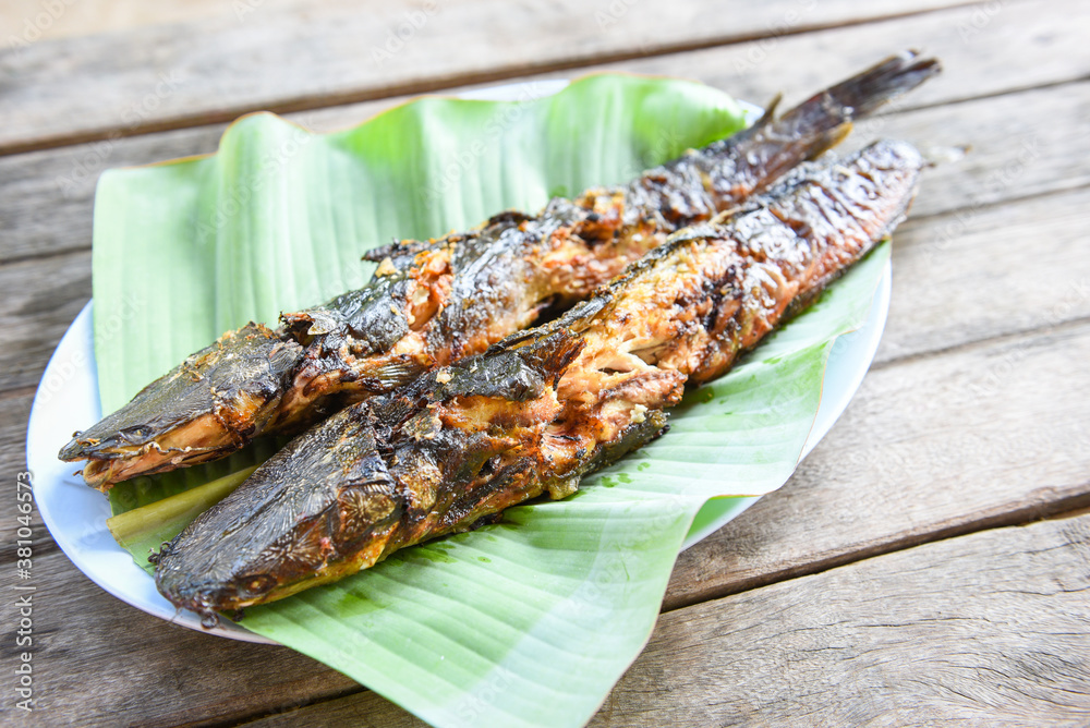 catfish roasted on banana leaf - cooked catfish grilled Asian food on wooden table catfish roasted on banana leaf - cooked catfish grilled Asian food on wooden table