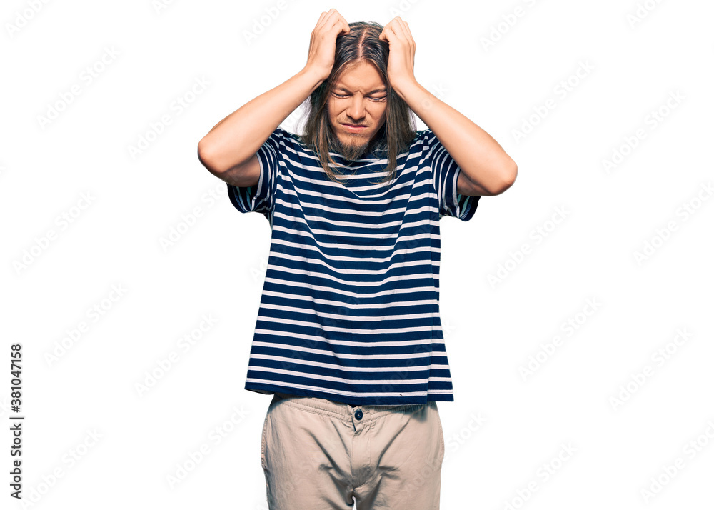 Handsome caucasian man with long hair wearing casual striped t-shirt suffering from headache desperate and stressed because pain and migraine. hands on head. Handsome caucasian man with long hair wearing casual striped t-shirt suffering from headache desperate and stressed because pain and migraine. hands on head.