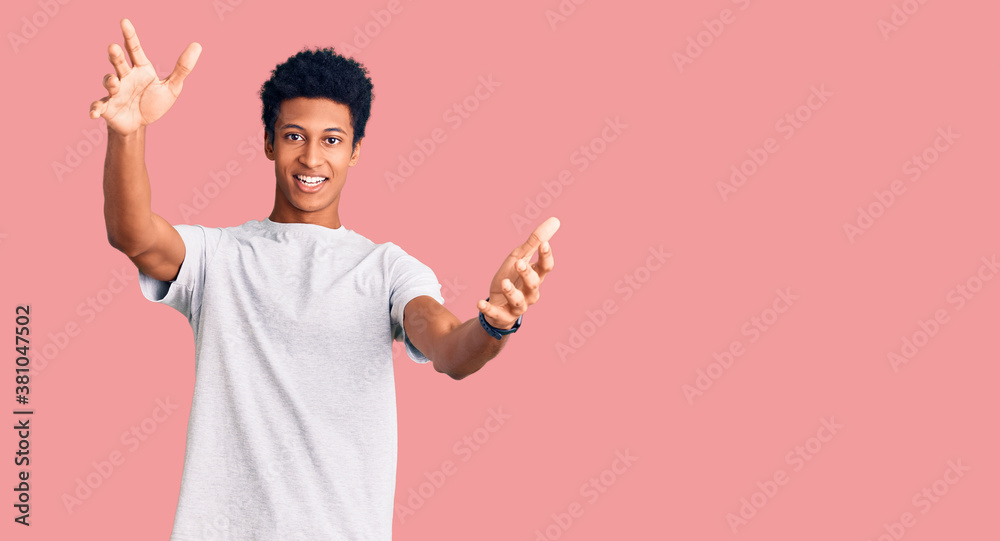 Young african american man wearing casual clothes looking at the camera smiling with open arms for hug. cheerful expression embracing happiness. Young african american man wearing casual clothes looking at the camera smiling with open arms for hug. cheerful expression embracing happiness.