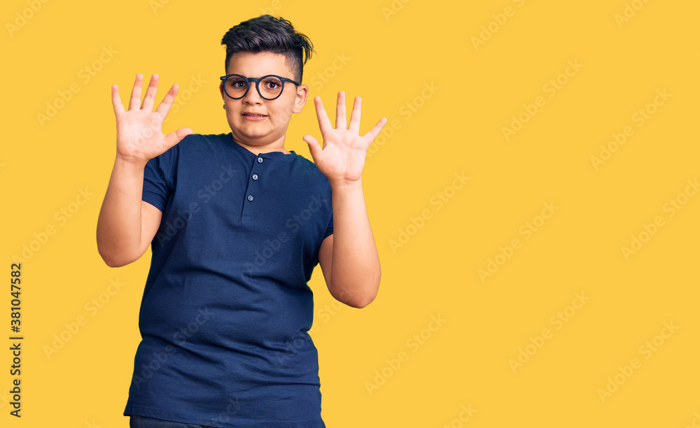Little boy kid wearing casual clothes and glasses afraid and terrified with fear expression stop gesture with hands, shouting in shock. panic concept. Little boy kid wearing casual clothes and glasses afraid and terrified with fear expression stop gesture with hands, shouting in shock. panic concept.