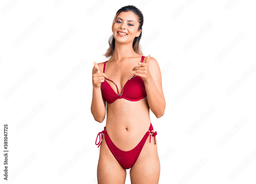 Young beautiful woman wearing bikini pointing fingers to camera with happy and funny face. good energy and vibes. Young beautiful woman wearing bikini pointing fingers to camera with happy and funny face. good energy and vibes.