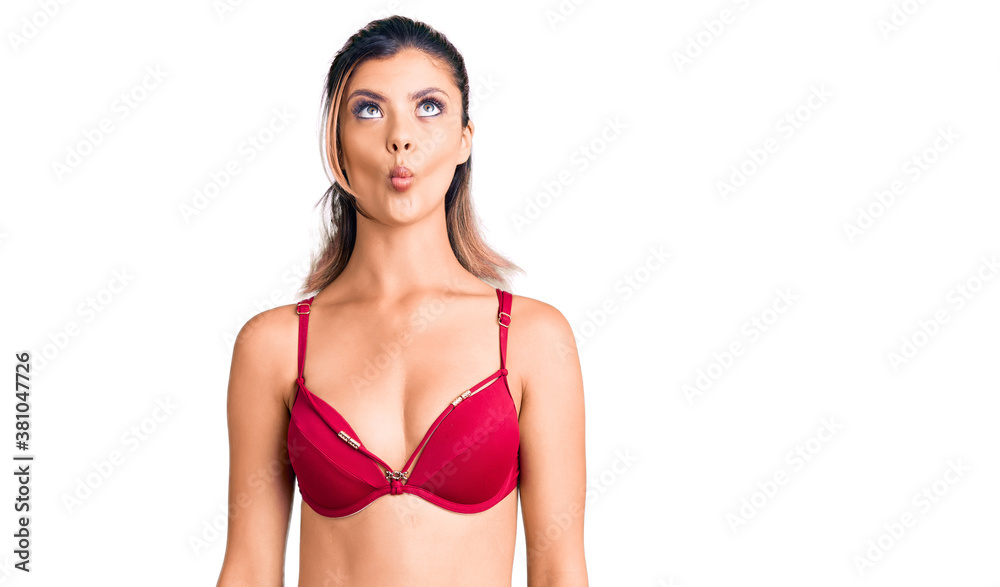 Young beautiful woman wearing bikini making fish face with lips, crazy and comical gesture. funny expression. Young beautiful woman wearing bikini making fish face with lips, crazy and comical gesture. funny expression.