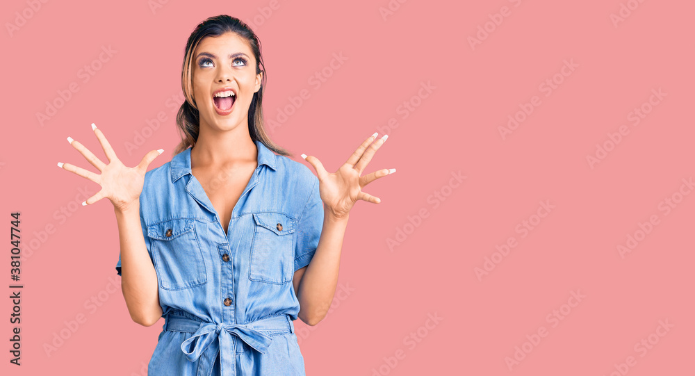 Young beautiful woman wearing casual clothes crazy and mad shouting and yelling with aggressive expression and arms raised. frustration concept. Young beautiful woman wearing casual clothes crazy and mad shouting and yelling with aggressive expression and arms raised. frustration concept.