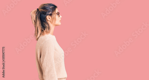 Young beautiful woman wearing casual winter sweater and glasses looking to side, relax profile pose with natural face with confident smile.