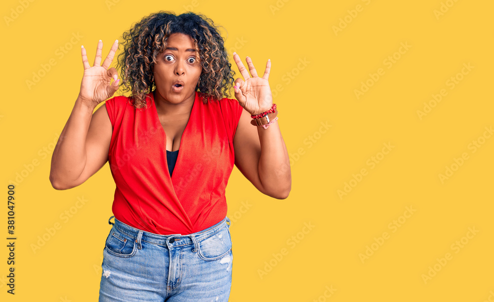 Young african american plus size woman wearing casual style with sleeveless shirt looking surprised and shocked doing ok approval symbol with fingers. crazy expression Young african american plus size woman wearing casual style with sleeveless shirt looking surprised and shocked doing ok approval symbol with fingers. crazy expression