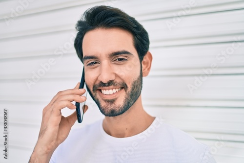 Young hispanic man smiling happy talking on the smartphone at city.