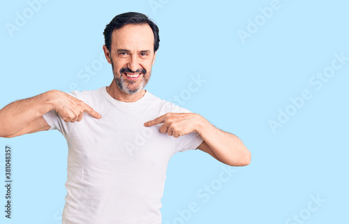 Middle age handsome man wearing casual t-shirt looking confident with smile on face, pointing oneself with fingers proud and happy.