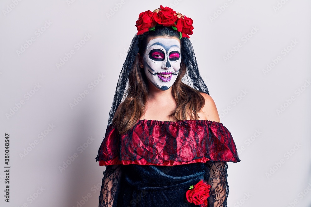Young woman wearing day of the dead costume over white winking looking at the camera with sexy expression, cheerful and happy face.