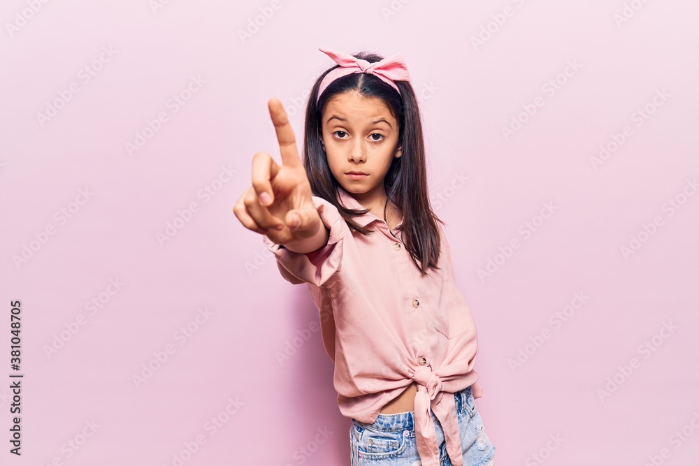 Beautiful child girl wearing casual clothes pointing with finger up and angry expression, showing no gesture
