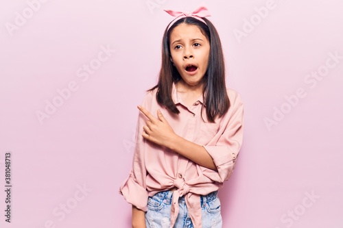 Beautiful child girl wearing casual clothes pointing aside worried and nervous with forefinger, concerned and surprised expression