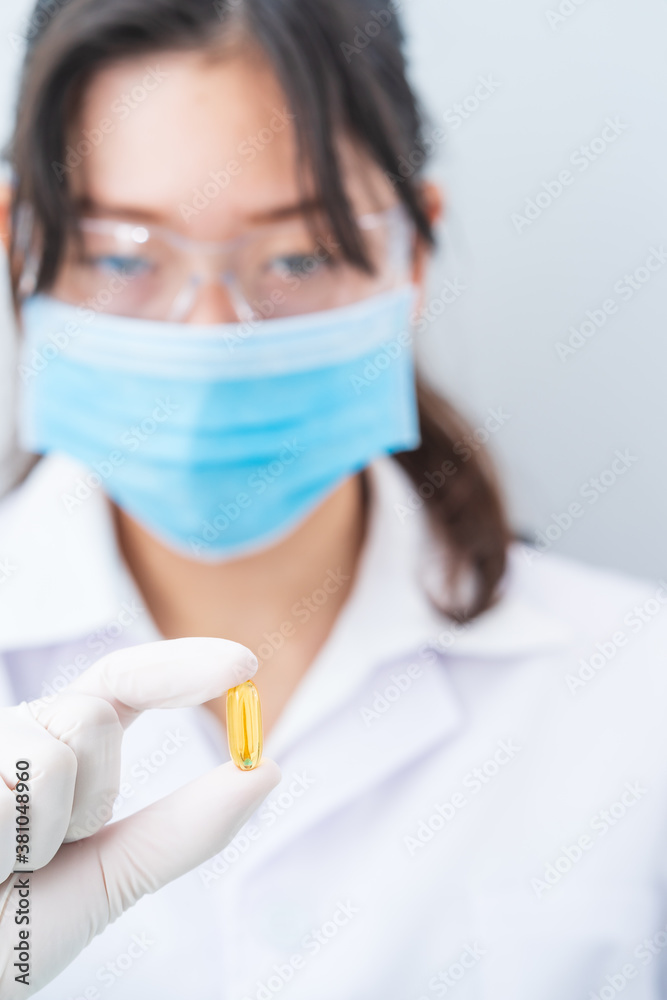 Close up Scientist holding Omega 3 capsule in labcoat Close up Scientist holding Omega 3 capsule in labcoat