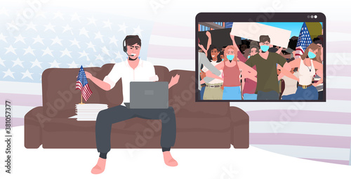 man using laptop watching online video people in masks holding usa flags labor day celebration coronavirus quarantine self isolation concept living room interior horizontal vector illustration