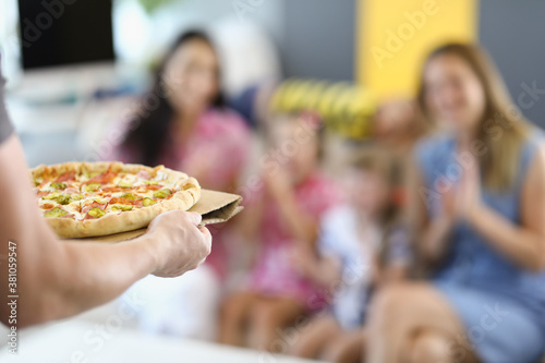 Male hands hold pizza on background of people. Fast delivery from pizzerias concept