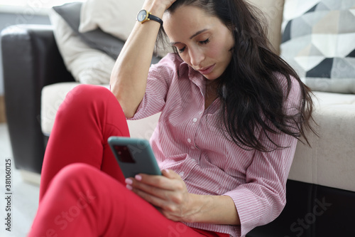 Depressed woman sits with closed eyes and holds smartphone in her hands. Stressful situations in women's life concept photo