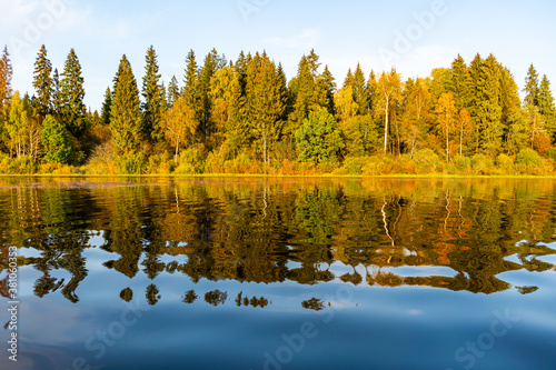 Lake with calm water. Beautiful autumn reflections with colorful foliage during sunset