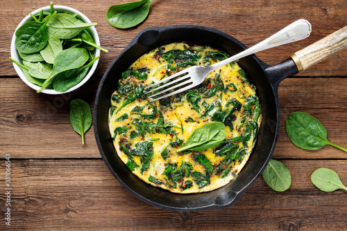 Omelette with baby spinach in cast iron pan, healthy breakfast . 
