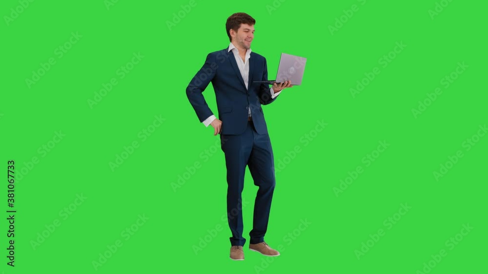 Smiling young businessman using laptop while standing on a Green Screen, Chroma Key. Smiling young businessman using laptop while standing on a Green Screen, Chroma Key.