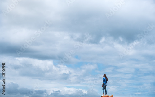 A female traveler standing on the mountain peak with blue sky background