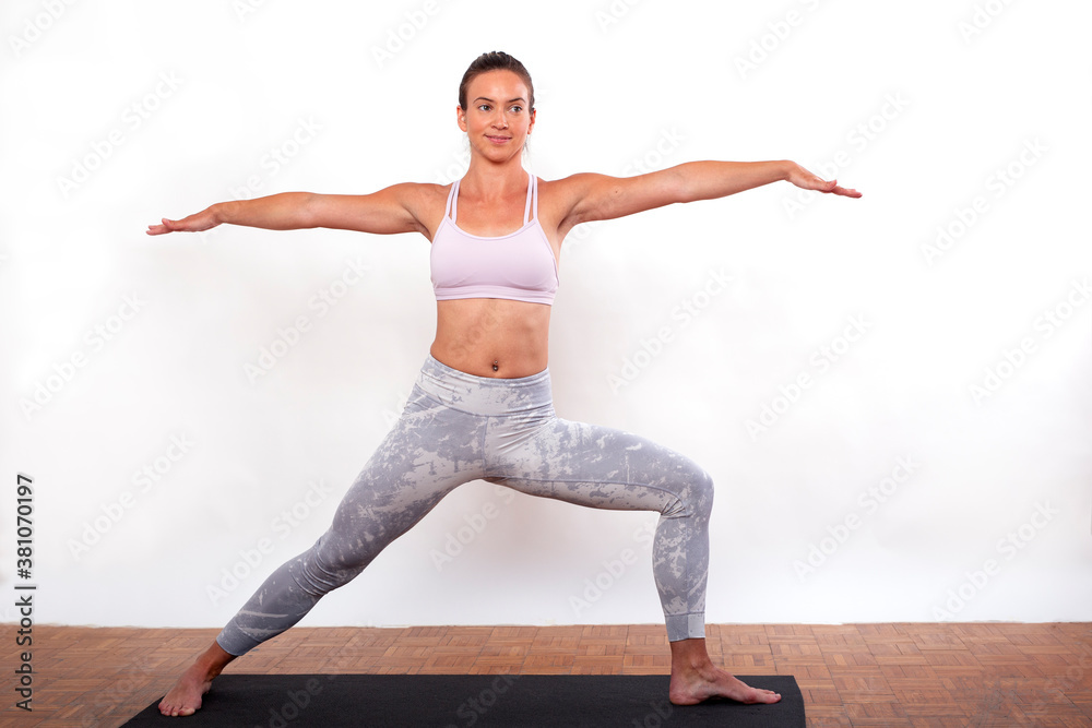 Young girl in home studio exercise yoga with flexible body making figures in front of white background