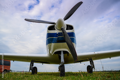 small single-engine civil airplane on a green grass of a countryside airdrome