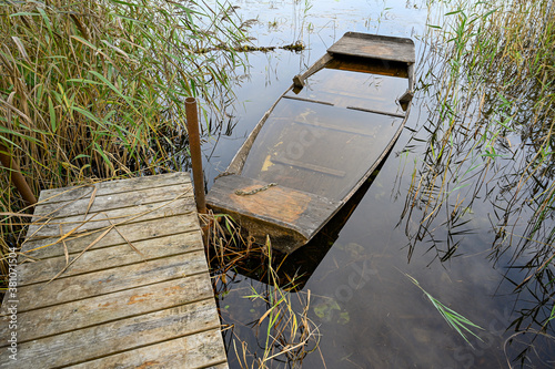 old wooden boat filled with water at jetty