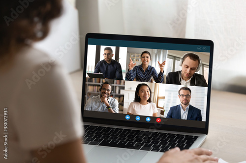Close up view of woman talk on video call on laptop with diverse multiracial colleagues. Female employee have webcam conference or digital virtual communication with coworker. Online meeting concept.