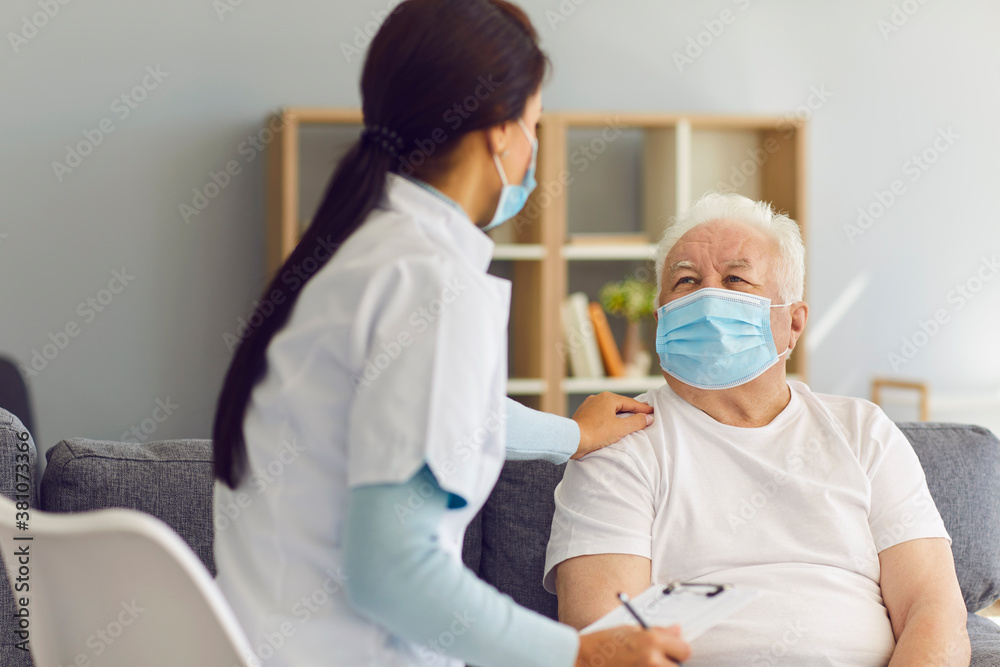 Fototapeta premium Caring supportive doctor visiting senior male patient at home during coronavirus pandemic