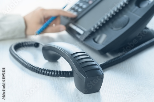 Business and communications. Using voip phone in the office, close up of hand with receiver. Conference call, contact us or hotline banner. IP telephony, Telemarketing. Help desk or call centre photo