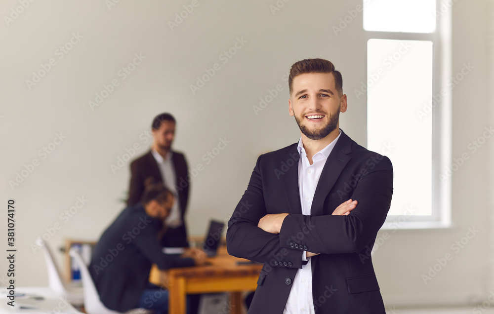 Smiling office worker or businessman looking at camera with colleagues working at background Smiling office worker or businessman looking at camera with colleagues working at background