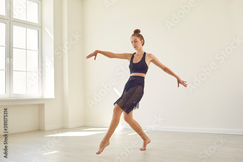 Fototapeta Naklejka Na Ścianę i Meble -  Serious concentrated young female dancer practicing alone in new modern dance studio