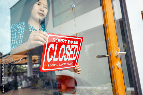 Closeup hand of Asian young woman setting Close sign at the shop glasses for welcome the customer in to the coffee shop, small business owner and startup, installing open and close label concept.