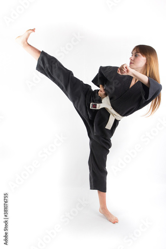 Girl in grey kimono karate training makes a high kick