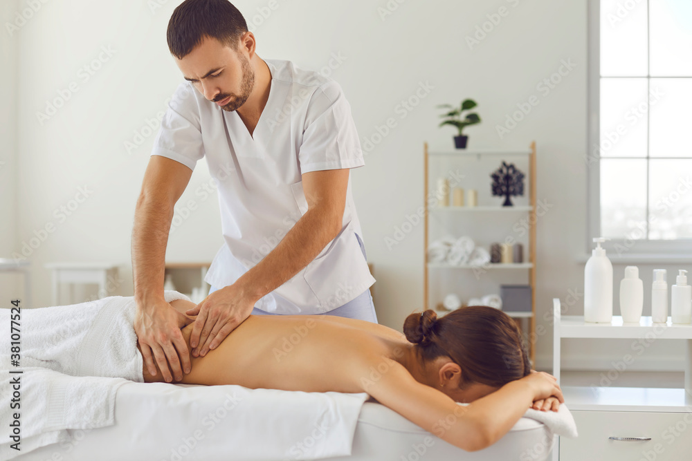 Professional masseur therapist doing therapeutic massage on the back of a female patient. - obrazy, fototapety, plakaty 