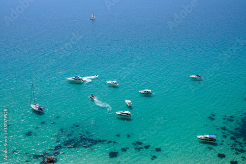 the yachts on the transparent blue water of a sea bay. The shadows of the ships and the boats lays on a sand bottom of the sea