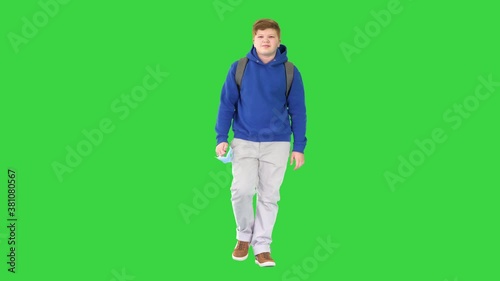 Teenager walking and taking off medical mask on a Green Screen, Chroma Key. photo