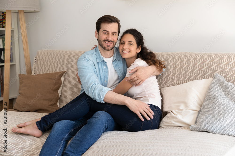 Portrait of happy young Caucasian man and woman tenants relax on sofa in cozy living room in new home. Smiling couple renters rest on couch, enjoy family weekend in own house. Realty concept. Portrait of happy young Caucasian man and woman tenants relax on sofa in cozy living room in new home. Smiling couple renters rest on couch, enjoy family weekend in own house. Realty concept.