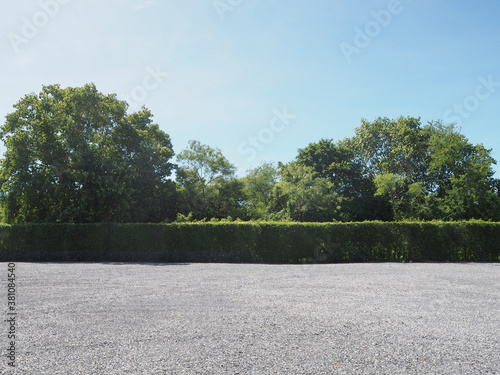 Parking lot sprinkled with gravel bush green tree blue sky nature background