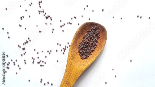 Mustard seeds in wooden spoon isolated 