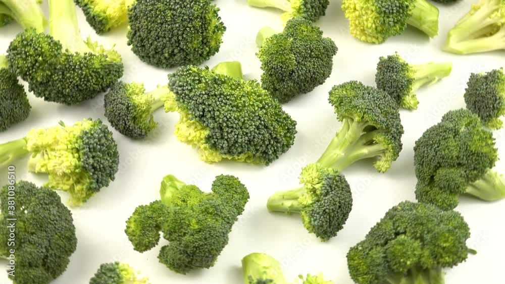 Pieces of fresh raw broccoli lie on a white table Pieces of fresh raw broccoli lie on a white table