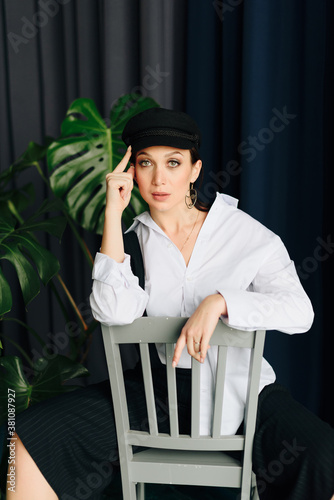 Portrait of a beautiful young woman in a white shirt and black trousers at home